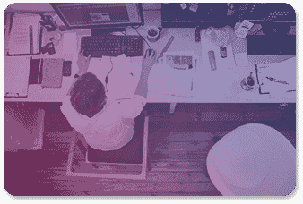A professional working on a PC with a clutter of papers on his desk